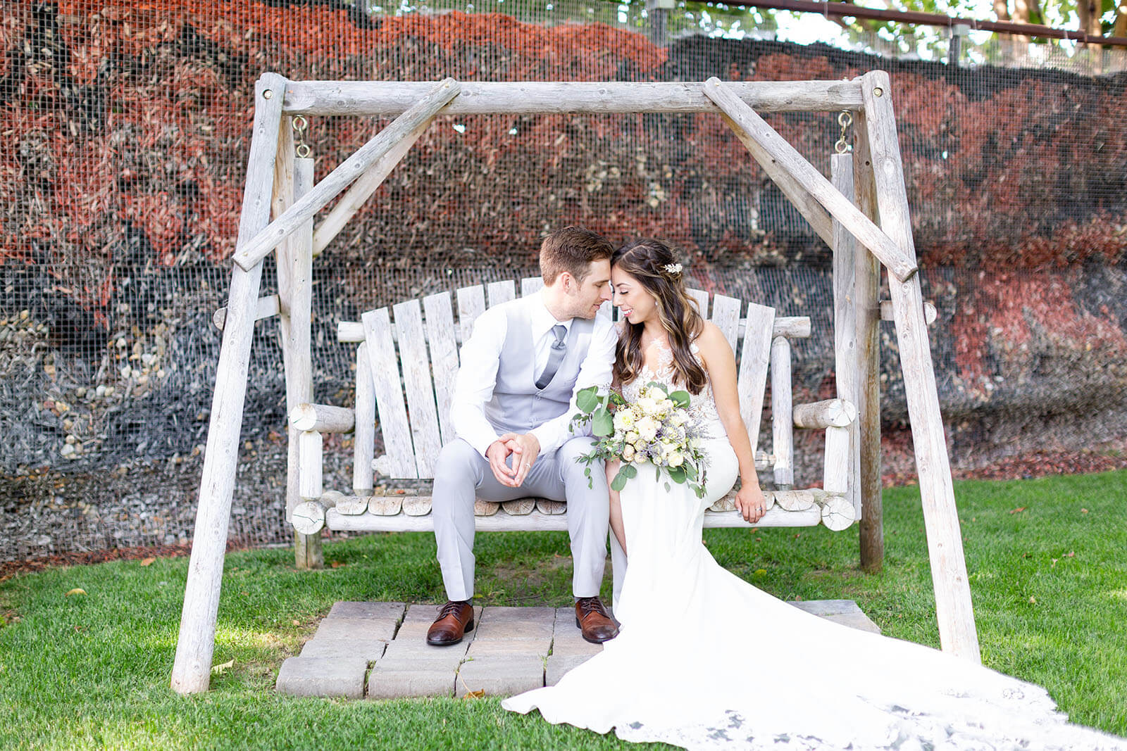 bride and groom sit on swing at Brownstone Gardens