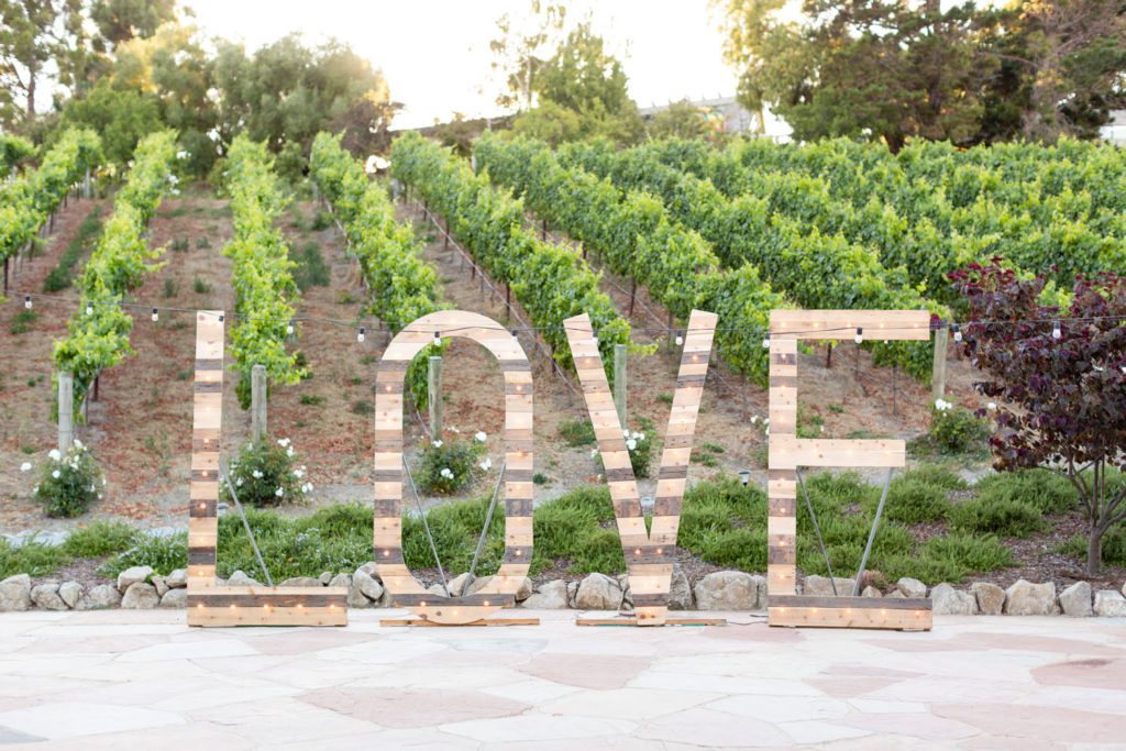 large wooden letter sign in front of vineyard: "LOVE"