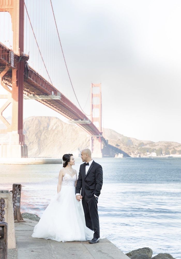 Bride and groom stand under Golden Gate Bridge