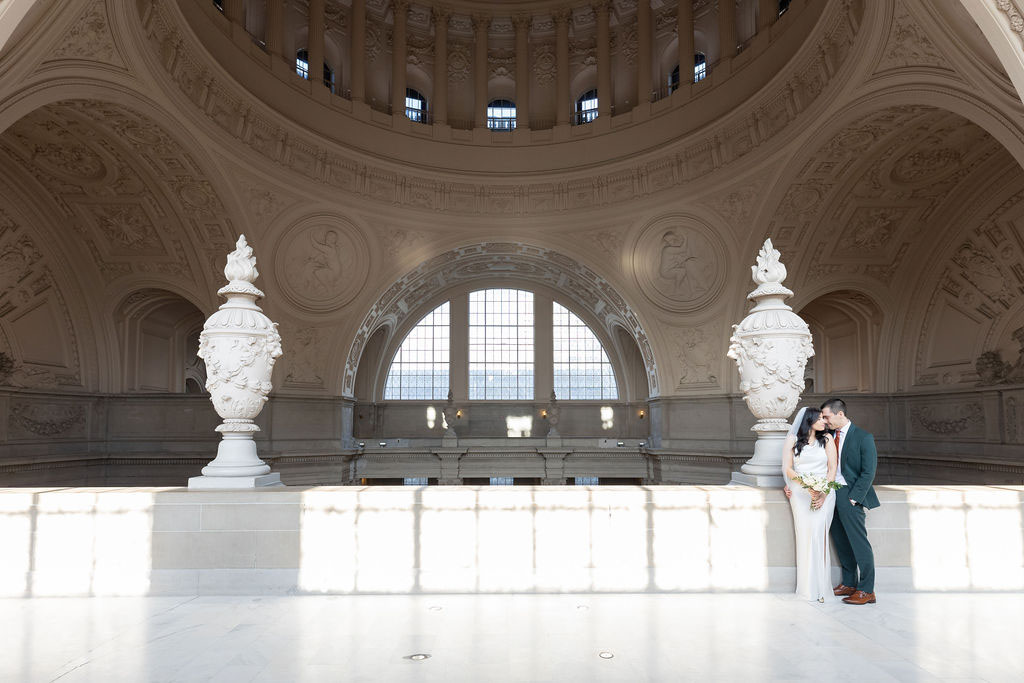 Fourth Floor SF City Hall wedding photo, with light coming in through windows and couple standing in shadow but still illuminated