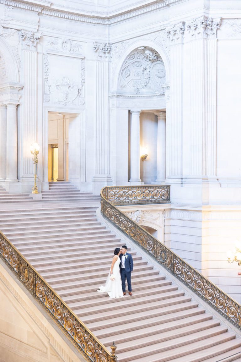 Couples stands alone and kisses on Grand Staircase of SF City Hall