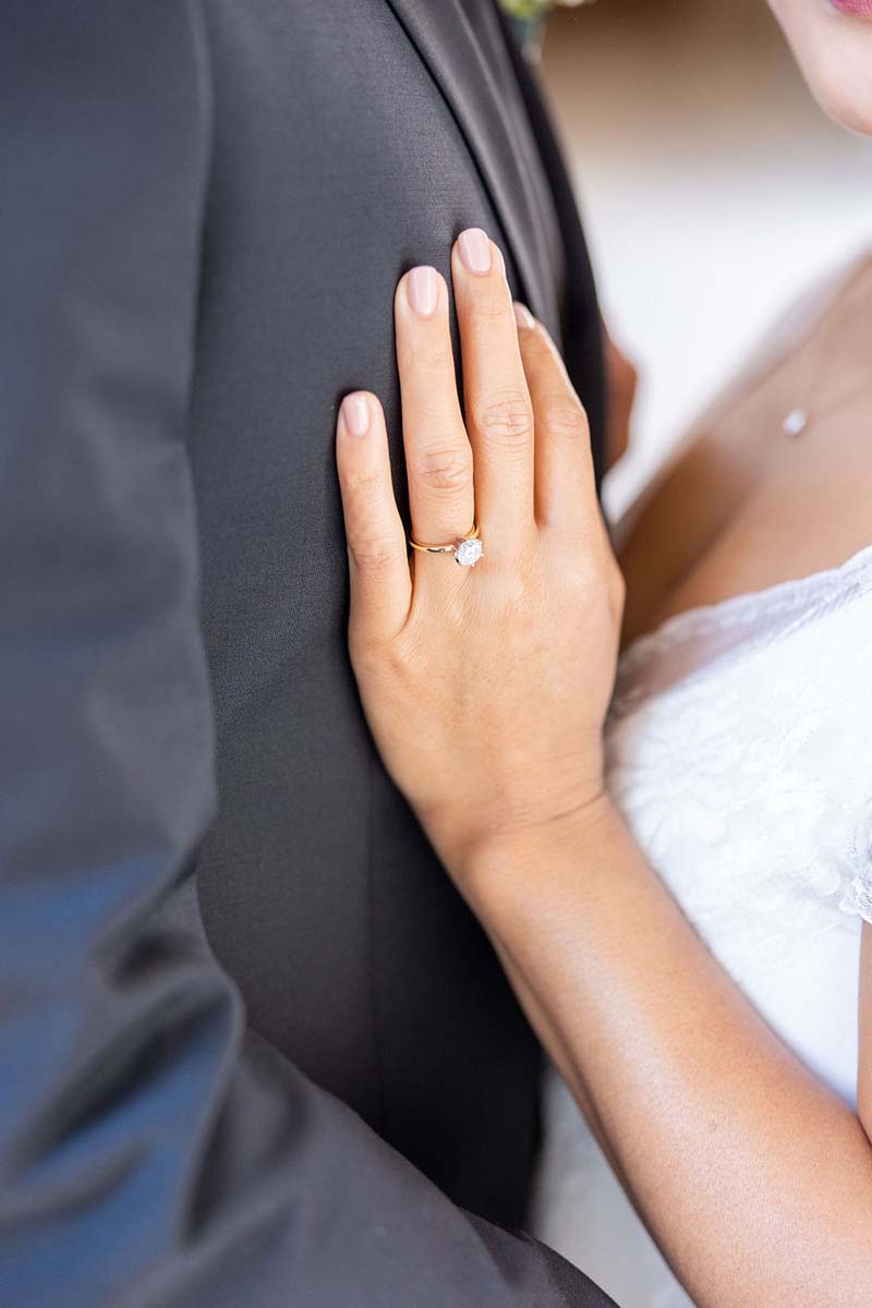 Closeup photo of bride's hand on groom's chest showing wedding ring